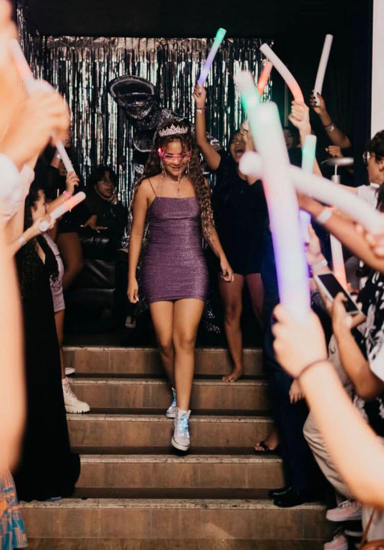 Entrada da debutante pela escada iluminada por bastões de LED erguidos pelos convidados