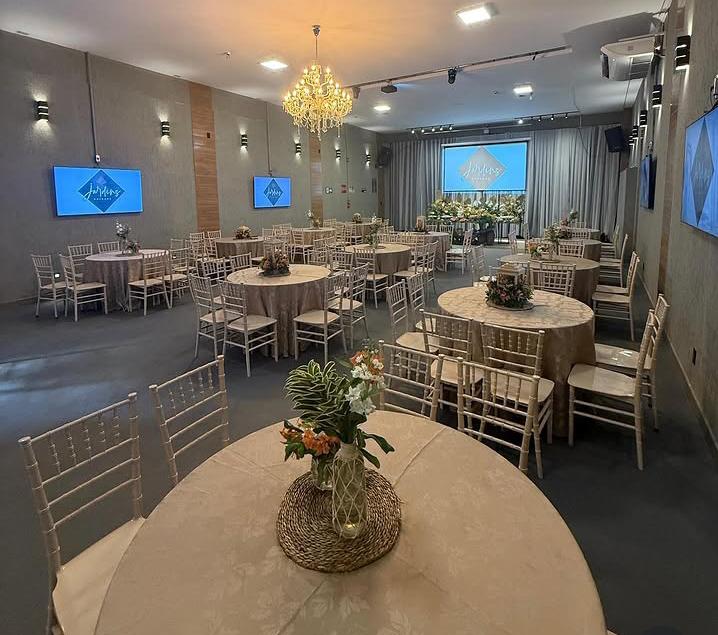 Salão com cadeiras chiavari, lustre, telões e sistema de som instalado